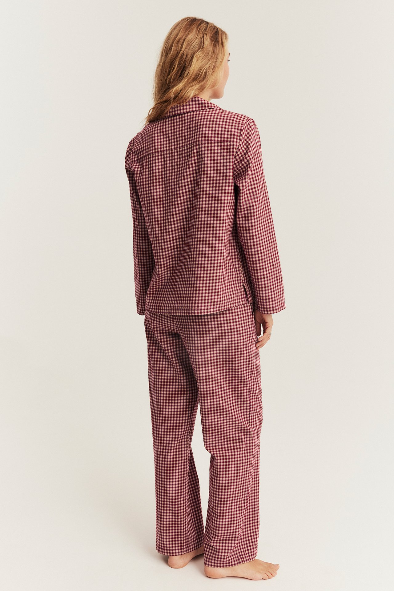 Back view of a woman wearing a red and white gingham check pajama set.