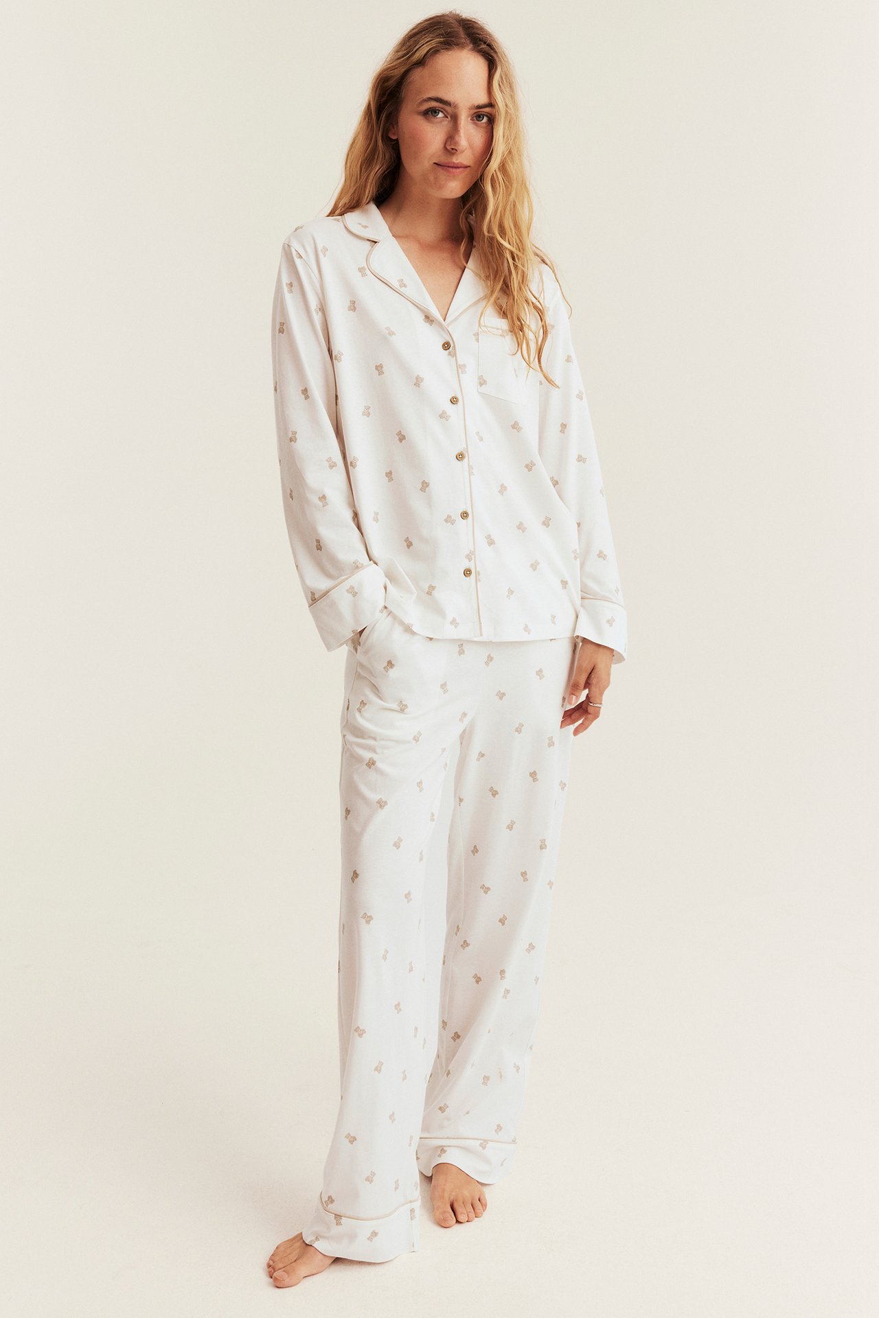 Front view of a woman wearing a white long-sleeve pajama set with brown bear print.
