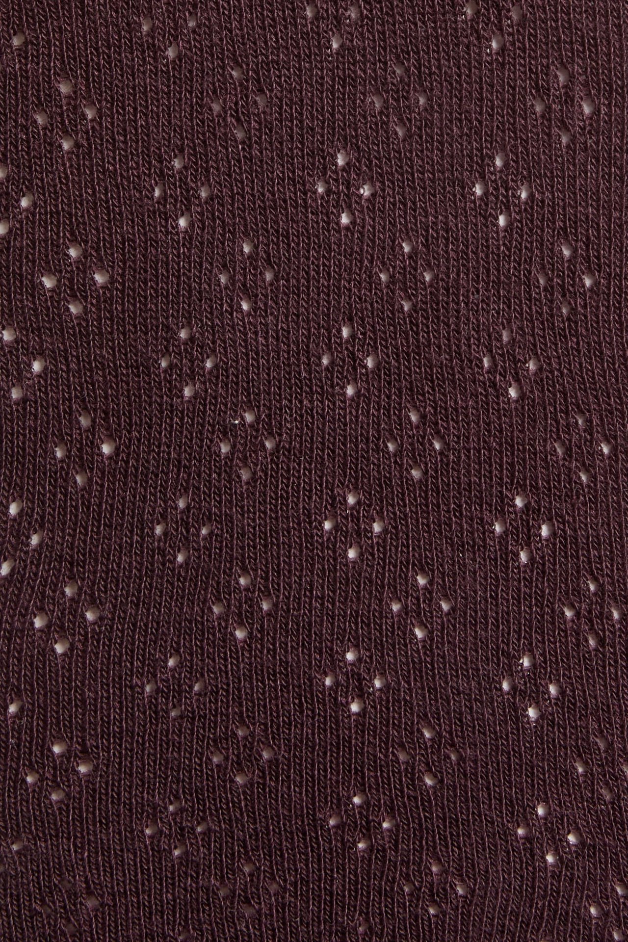 Nahaufnahme von dunkelrotem Strickstoff mit kleinen weißen Lochstickereien.