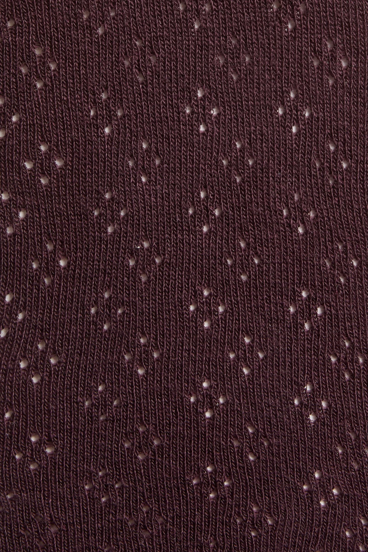 Nahaufnahme von dunkelrotem Strickstoff mit kleinen weißen Lochstickereien.