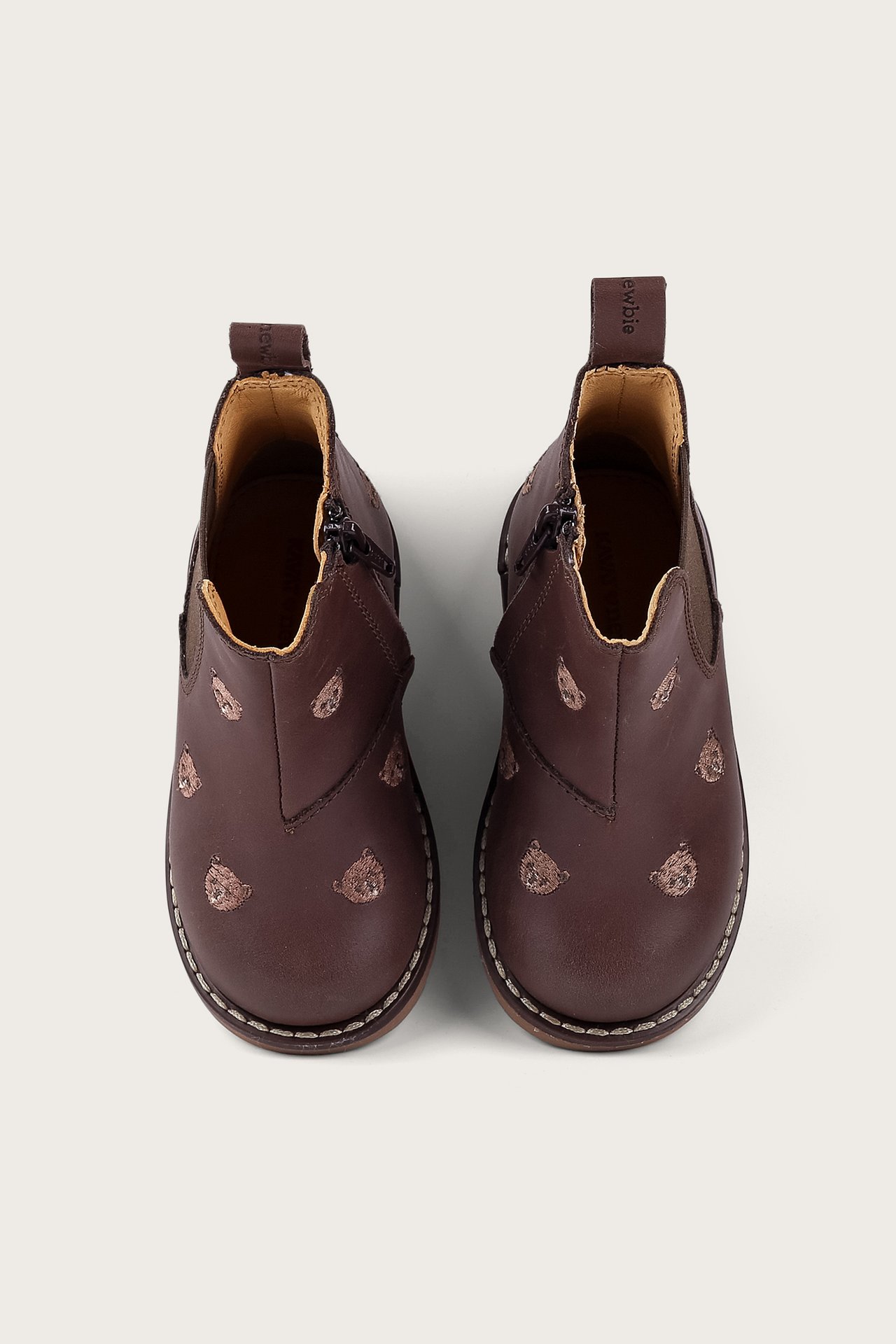 Draufsicht auf dunkelbraune Kinder-Stiefeletten mit hellbraunen Stickmustern und Reißverschlüssen.