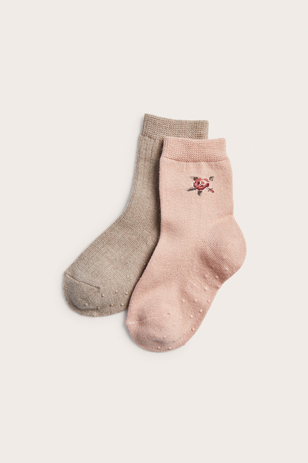 Two pairs of baby socks; one pink with rose embroidery, one beige, both with anti-slip grips.
