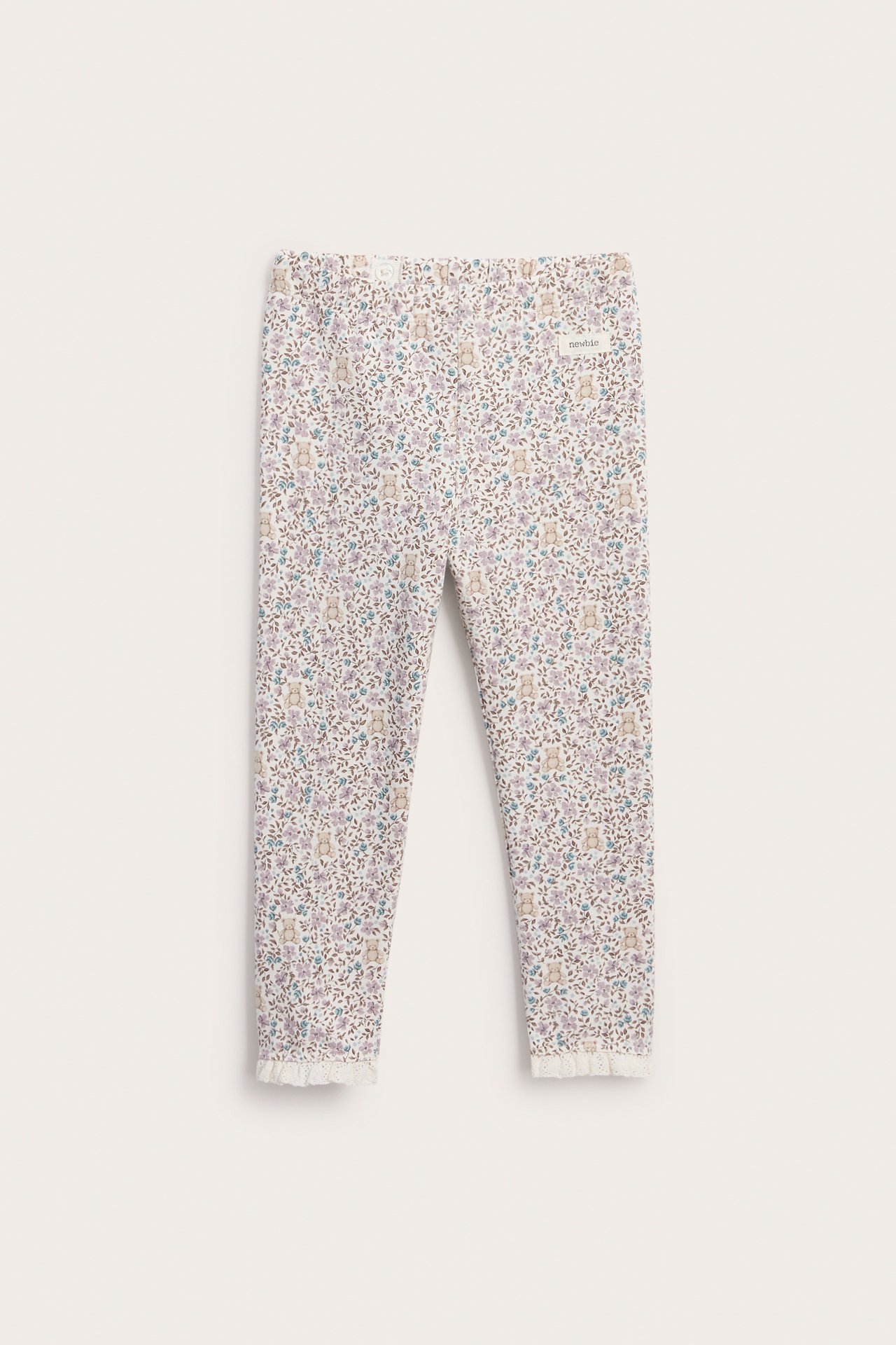 Vorderansicht von Baby-Leggings mit hellem Blumen- und Bärchenmuster und Spitzenbesatz an den Knöcheln.