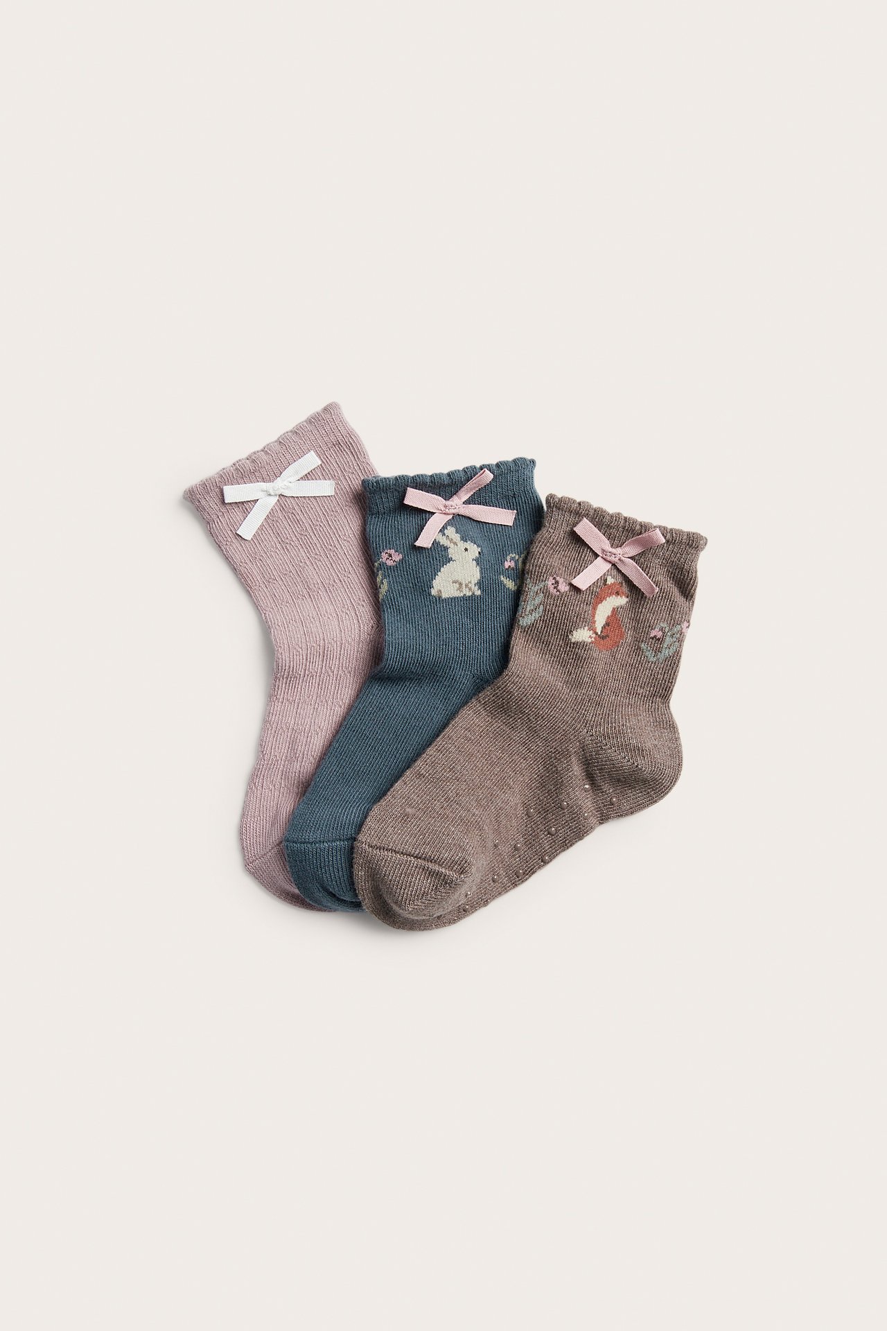 Drei Kindersocken: rosa mit weißer Schleife, petrol Hase mit rosa, brauner Fuchs mit rosa.
