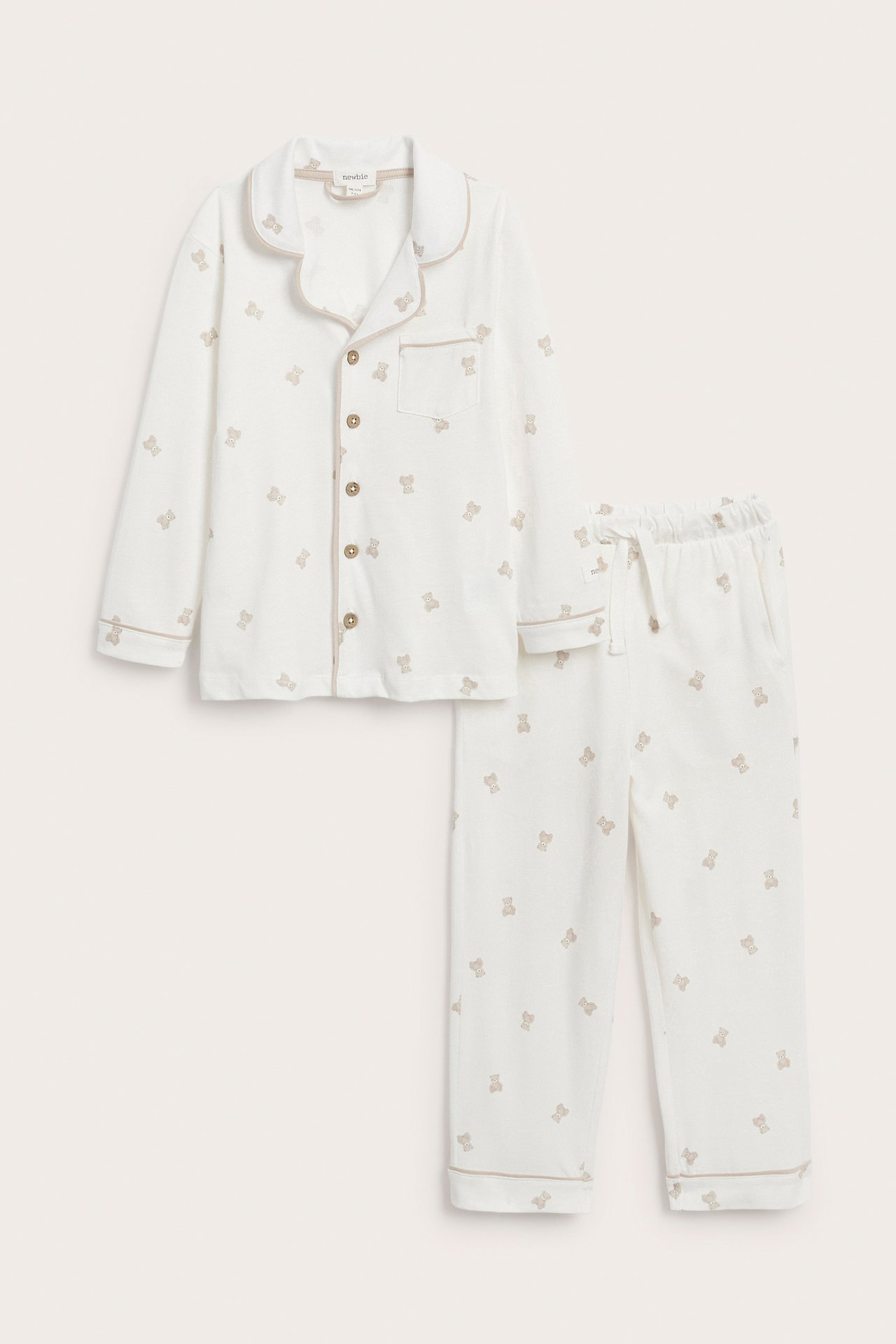 Vorderansicht eines weißen Baby-Schlafanzugs mit braunem Teddybär-Print und Paspeln.
