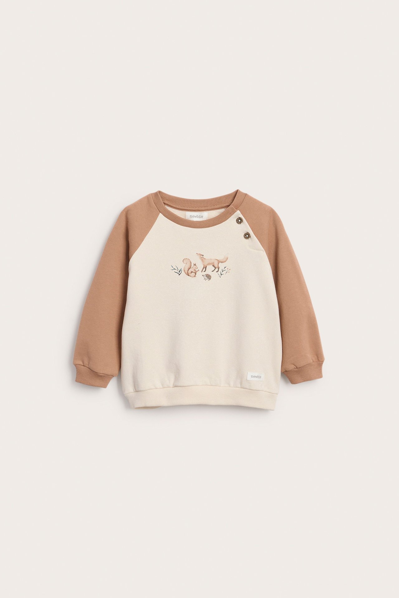Front view of a baby's off-white and brown raglan sweatshirt with forest animal embroidery and shoulder buttons.
