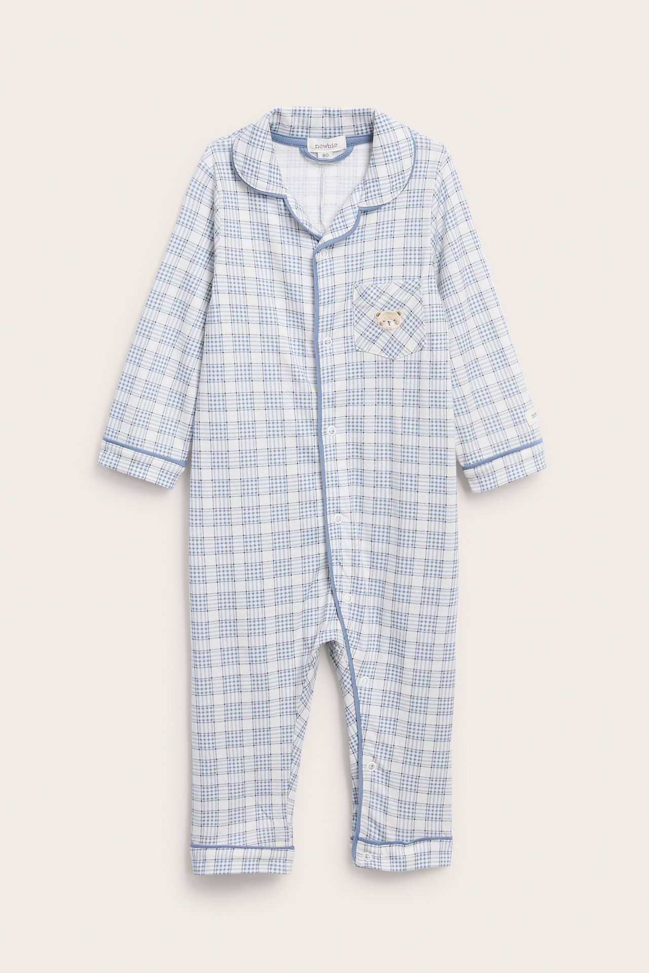 Vorderansicht eines weiß-blau karierten Baby-Stramplers mit Teddybär-Tasche.