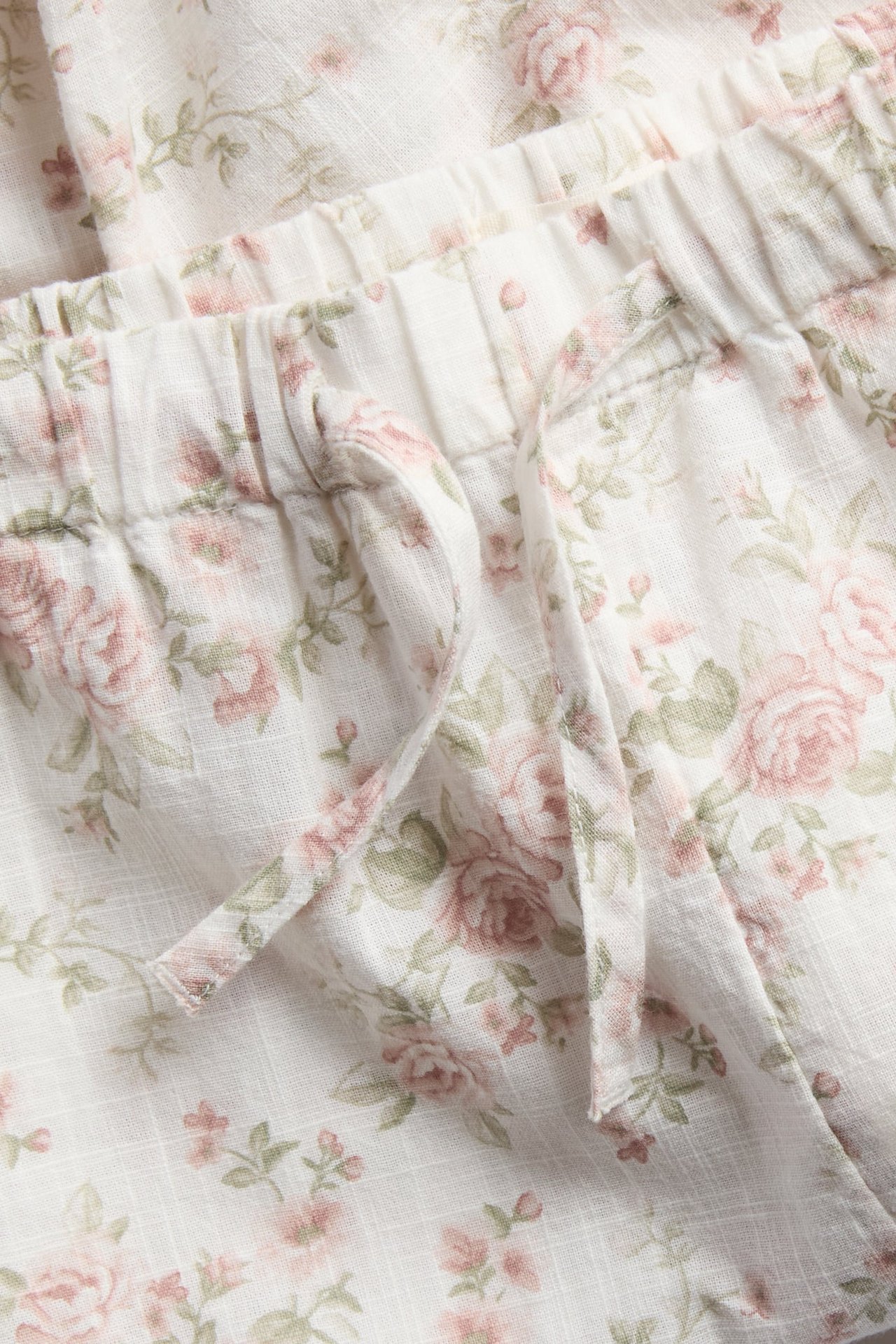 Close-up of white floral patterned shorts with elasticated drawstring waist in textured fabric.