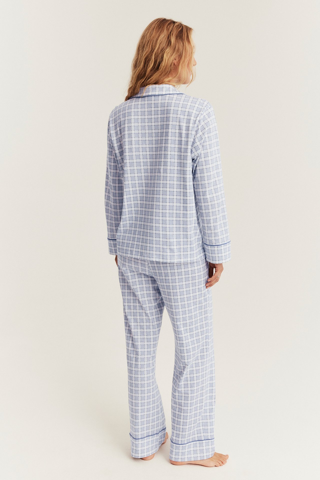 Back view of a woman wearing a blue and white plaid pajama set.